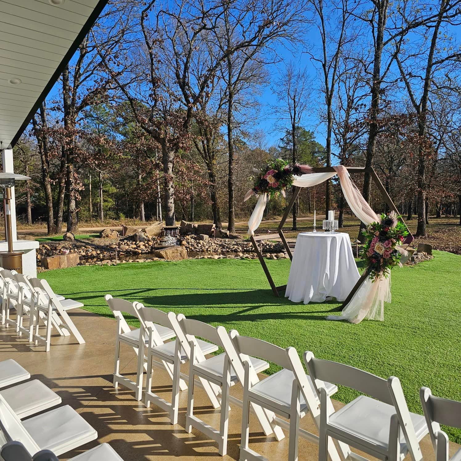 An outdoor wedding setup featuring a decorated altar and white chairs on a lawn.