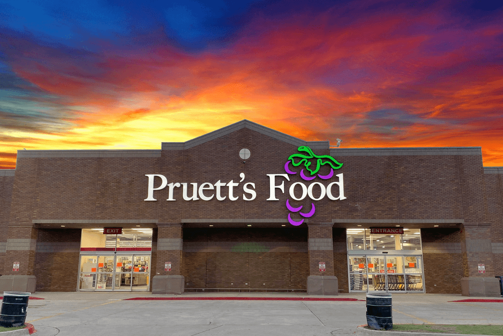 Storefront of Pruett's Food with a colorful sunset sky in the background.