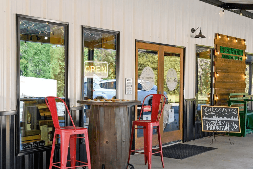 Outdoor entrance to Hochatown Mountain Co. featuring red metal chairs and an "Open" sign.